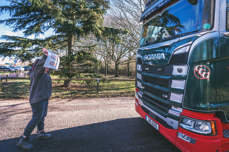 Activist holds a sign saying Murder House in front of a moving slaughterhouse truck - Dunbia Cardington Slaughterhouse, Bedford